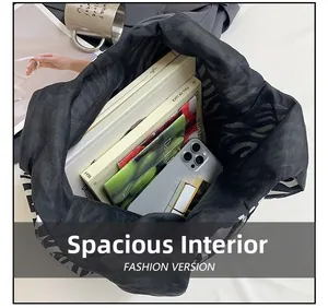 Internal view of a black tote bag showing its large capacity with books and phone