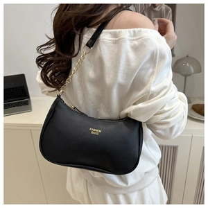 Close-up of black lychee grain leather underarm bag with gold chain and fashion text