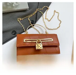 Detailansicht der karamellfarbenen Krokodiltasche mit goldenem Herzverschluss und Kette