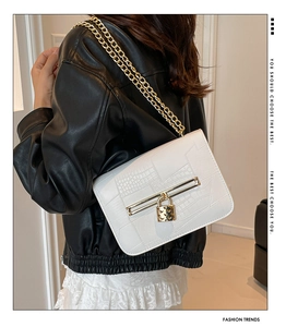 Close-up of white croc-effect leather bag with gold heart lock and chain strap