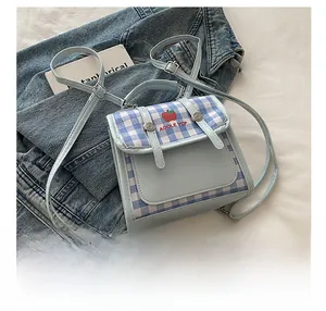 Detail show of blue plaid backpack with apple motif and thin straps on denim background