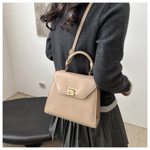 Beige PU leather crossbody bag with gold buckle on a model wearing a grey sweater