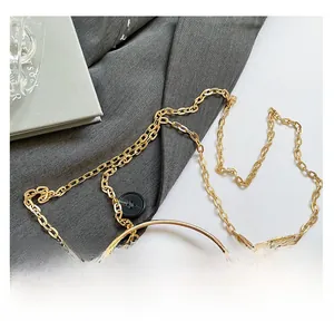 Detail einer braunen Krokodilledertasche mit Goldkette und rundem Metallgriffstück