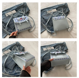 Detailed close-up of light blue backpack with apple embroidery and checkered flap design