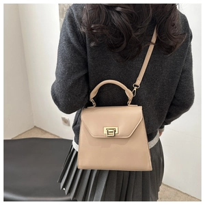 Detail of light beige crossbody bag featuring a golden square twist lock and smooth leather