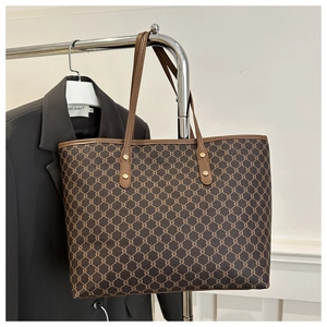 Detail of vintage monogram tote bag hanging on a rack showing leather handles and rivets