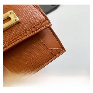 Detail der braunen Tasche mit Krokodilprägung, goldener Schnalle und Naht