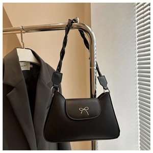 Detail of black leather underarm bag featuring a metal bow and woven strap design