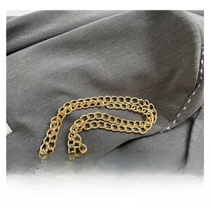 Detail of light gold double-row metal chain strap on minimalist underarm shoulder bag