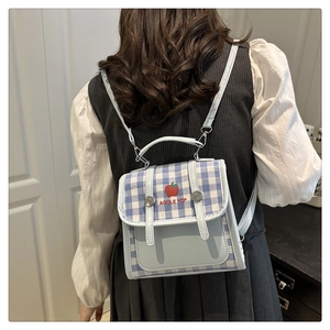 Detail of blue plaid mini backpack featuring red apple embroidery and slim straps