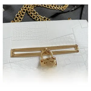 Detail of white crocodile embossed texture with heart-shaped golden lock on a small bag