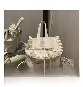 Detail view of cream backpack featuring lace trim, a bow, and a pearl metal pendant charm
