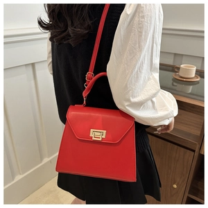 Chic red faux leather crossbody bag with gold buckle shown in a lifestyle indoor setting