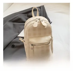 Detail eines beigen Rucksacks aus geprägtem Leder mit Karomuster und Doppelreißverschluss