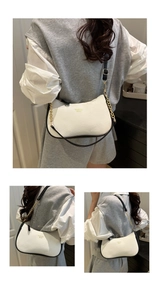 Detail of white lychee texture hobo bag with gold chain and black contrast piping