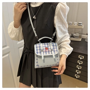 Close-up of blue checkered crossbody bag featuring red apple embroidery and top handle