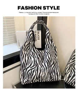 Detailweergave van zebraprint tote bag met geplooide handvaten op een moderne stoel