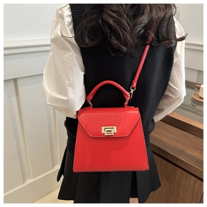 Fashionable red leather tote bag with gold swivel lock shown worn as a crossbody purse