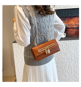 Detail of caramel embossed leather handbag with golden ring handle and heart lock