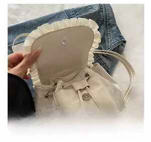Detailed view of cream ruffled drawstring bucket bag with silver magnetic snap closure