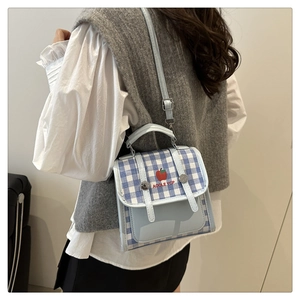 Detail of light blue plaid shoulder bag with apple print and silver metal buckles