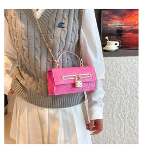 Detail of pink crocodile embossed handbag with gold chain and metal padlock clasp
