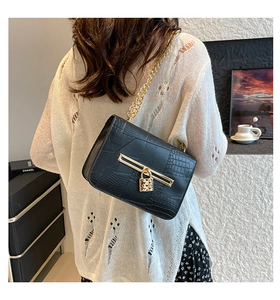 Detail of black crocodile texture shoulder bag with gold chain and heart lock charm