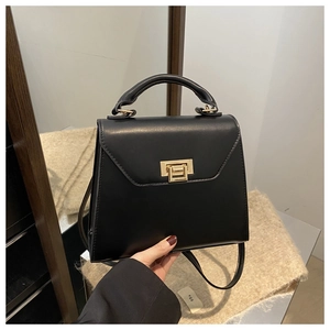Detail of black leather handbag with round top handle and golden rectangle twist lock