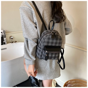 Detail des Mini-Rucksacks mit grau-schwarzem Karomuster und Lederriemen am Model