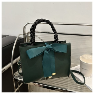 Detail of dark green square handbag with silk bow and gold metal hardware hooks