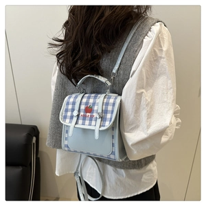 Detail of blue gingham school bag showing red apple embroidery and versatile straps