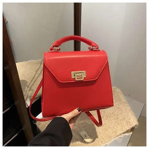 Detail of red leather handbag with gold twist lock and crossbody strap close-up