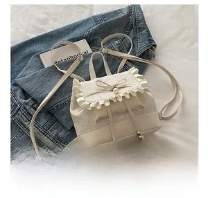 Mini white backpack with ruffles and bow decoration showing size comparison to a phone