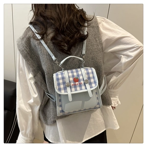 Detailed view of mini blue plaid backpack with apple pattern on back of model outfit