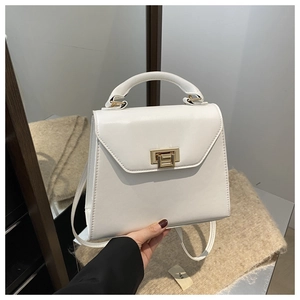 Detailed view of white textured handbag with elegant gold square rotating lock and strap