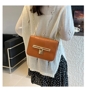 Detail of brown faux crocodile crossbody bag with gold chain and heart lock pendant