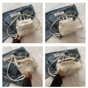 Detail view of white drawstring backpack with lace edges, ruffles, and pearl accents