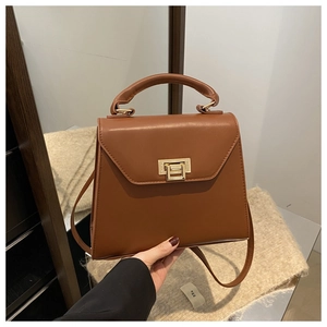 Close-up of brown leather handbag with golden twist lock and elegant top handle