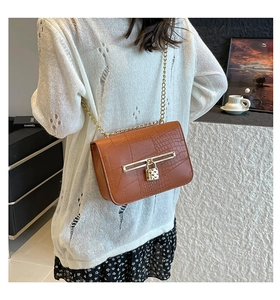 Brown crocodile texture crossbody bag with gold chain strap shown on a model