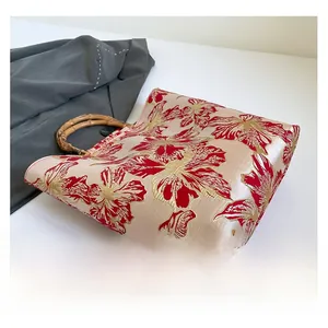 Close-up of golden floral embroidery and natural bamboo handle on tote bag