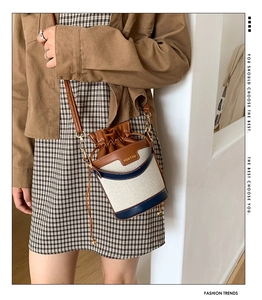 Détail du sac seau en toile et cuir avec cordon de serrage porté par un mannequin