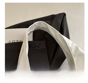 Detail view of the wide soft leather handle on a minimalist white tote bag for women