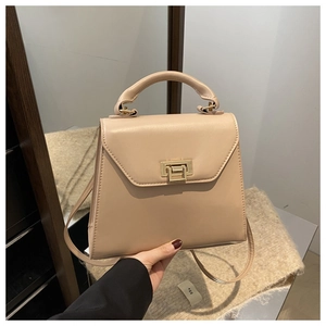 Detail of minimalist beige trapezoid handbag with a golden square metal clasp and top handle