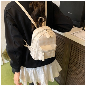Detail eines Mini-Rucksacks mit Karomuster und Lederriemen auf dem Rücken des Models