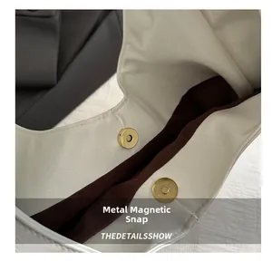 Detail view of the magnetic gold snap closure on the white leather shoulder handbag