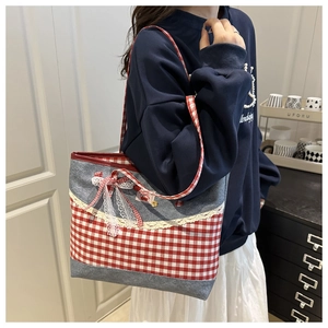 Détail du nœud à carreaux rouges et dentelle blanche sur sac fourre-tout gris