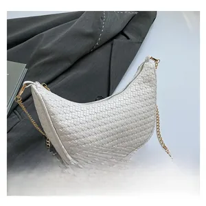 Close-up of white crescent bag with woven checkered texture and gold metal chain