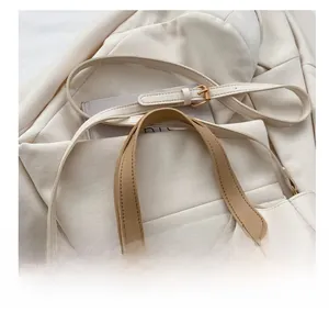 Détail de la bandoulière réglable camel avec boucle en métal doré sur cabas blanc