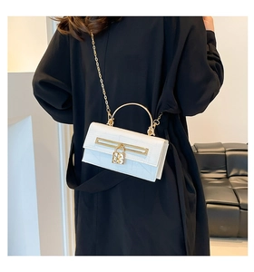 White croc-pattern chain bag with gold handle shown against a black outfit background
