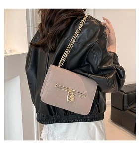 Detail view of pink leather handbag with crocodile pattern and golden metal chain strap